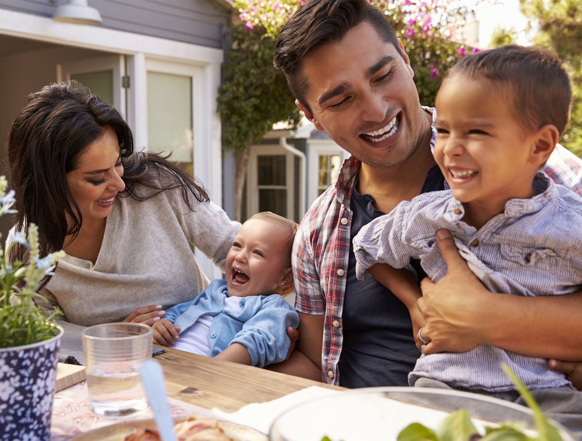 Familia riendo alrededor de una mesa al aire libre